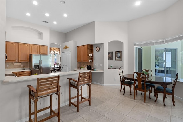 2026 Winding Oaks Dr, Orlando, FL 32825 - kitchen featuring stainless steel refrigerator with ice dispenser, arched walkways, a towering ceiling, recessed lighting, and light countertops