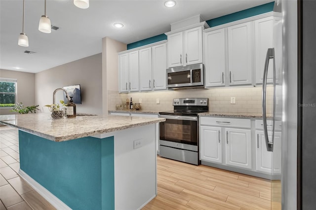 2936 Econ Landing Blvd, Orlando, FL 32825 - kitchen featuring stainless steel appliances, white cabinetry, tasteful backsplash, an island with sink, and pendant lighting