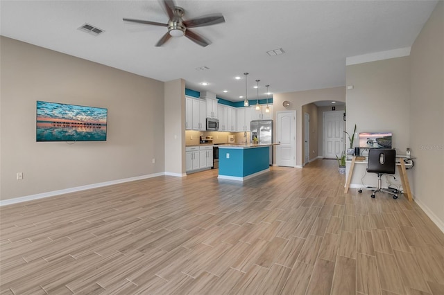 2936 Econ Landing Blvd, Orlando, FL 32825 - unfurnished living room featuring arched walkways, a ceiling fan, baseboards, light wood finished floors, and a desk