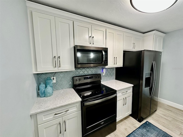 200 S Banana River Blvd Unit 703, Cocoa Beach, FL 32931 - kitchen featuring stainless steel microwave, range with electric stovetop, black refrigerator with ice dispenser, decorative backsplash, and light wood-style flooring