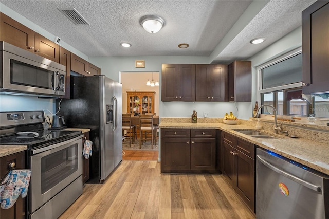 3362 Partridge St, Deltona, FL 32738 - kitchen featuring stainless steel appliances, a sink, dark brown cabinetry, light wood-style flooring, and a textured ceiling
