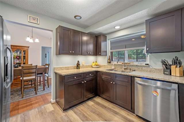 3362 Partridge St, Deltona, FL 32738 - kitchen with stainless steel appliances, a sink, light wood-style floors, dark brown cabinetry, and a textured ceiling