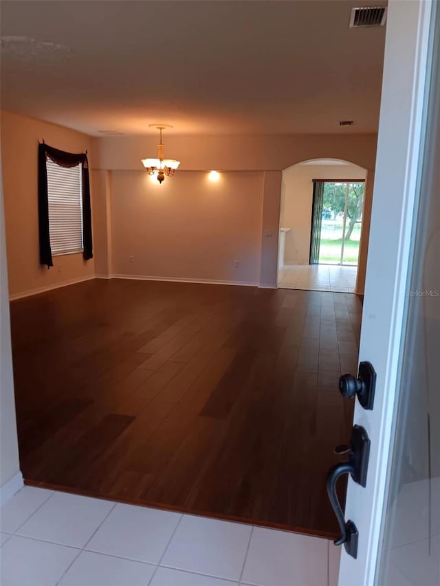 10415 Lucaya Dr, Tampa, FL 33647 - unfurnished room with arched walkways, wood finished floors, a chandelier, and baseboards