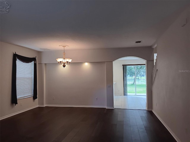 10415 Lucaya Dr, Tampa, FL 33647 - unfurnished room with arched walkways, a chandelier, dark wood-style floors, and baseboards