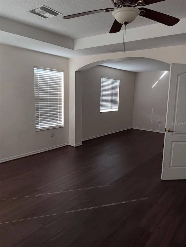 10415 Lucaya Dr, Tampa, FL 33647 - unfurnished room featuring ceiling fan, arched walkways, dark wood-type flooring, baseboards, and a textured ceiling