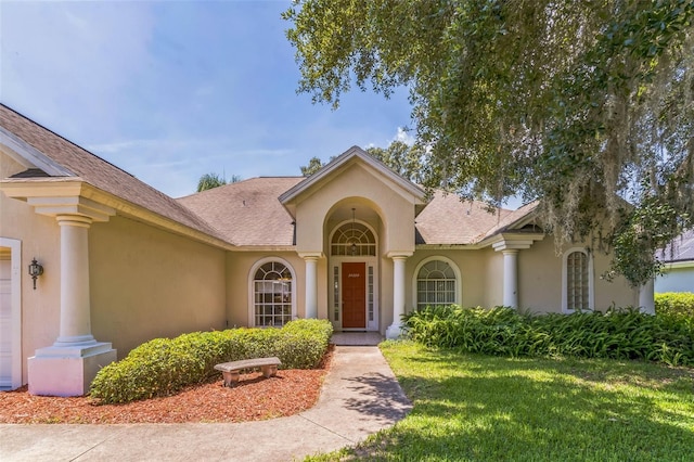 34239 Woodridge Ln, Eustis, FL 32736 - view of front of home featuring stucco siding, a front lawn, and roof with shingles