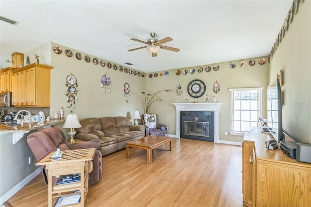 34239 Woodridge Ln, Eustis, FL 32736 - living area with a ceiling fan, light wood finished floors, a glass covered fireplace, and baseboards