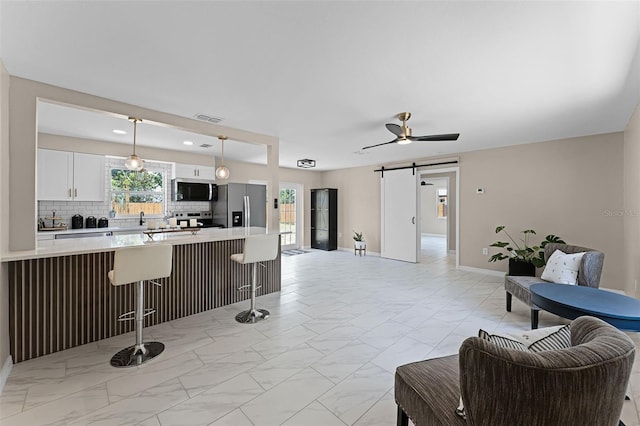 410 W Seminole Ave, Eustis, FL 32726 - living room featuring light marble finish floors, a barn door, baseboards, and ceiling fan