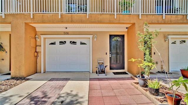 5016 W Lancaster St Unit 00, Tampa, FL 33616 - doorway to property featuring a garage, stucco siding, a balcony, and concrete driveway