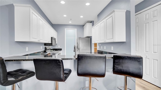 5016 W Lancaster St Unit 00, Tampa, FL 33616 - kitchen featuring stainless steel appliances, white cabinetry, recessed lighting, a peninsula, and a kitchen bar