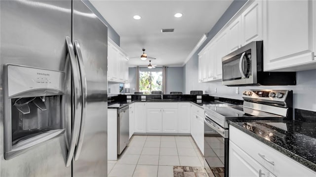 5016 W Lancaster St Unit 00, Tampa, FL 33616 - kitchen with stainless steel appliances, light tile patterned flooring, white cabinetry, a sink, and dark stone counters