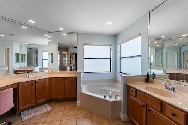 1716 Wild Indigo Ter, Oviedo, FL 32766 - bathroom with a textured ceiling, a garden tub, two vanities, a stall shower, and tile patterned floors