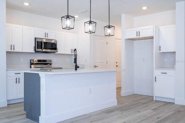 509 St Johns Ct, Poinciana, FL 34759 - kitchen featuring appliances with stainless steel finishes, tasteful backsplash, white cabinets, light countertops, and pendant lighting