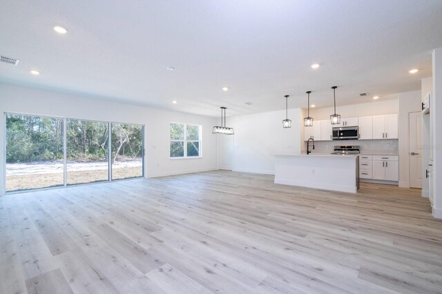 509 St Johns Ct, Poinciana, FL 34759 - unfurnished living room with recessed lighting, light wood-style flooring, a sink, and baseboards