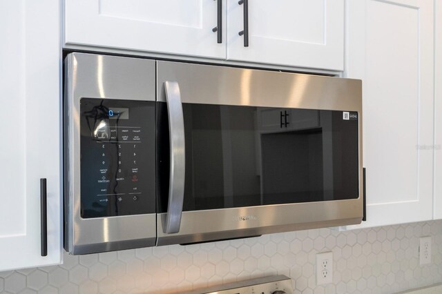 509 St Johns Ct, Poinciana, FL 34759 - kitchen view of stainless steel microwave, white cabinets, and decorative backsplash