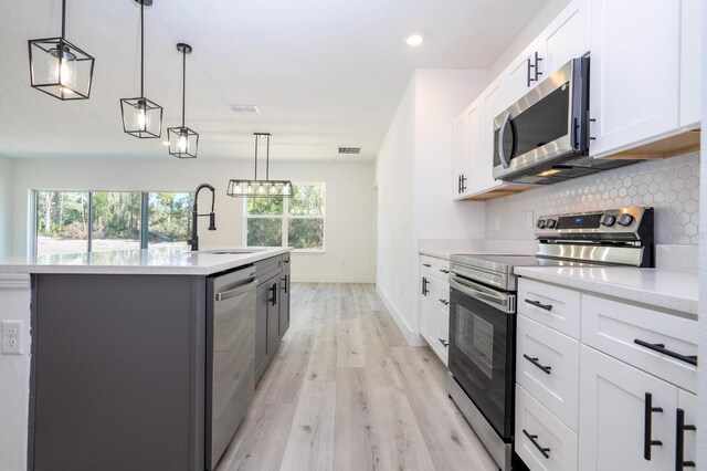 509 St Johns Ct, Poinciana, FL 34759 - kitchen with appliances with stainless steel finishes, a sink, decorative backsplash, light wood-style flooring, and light countertops