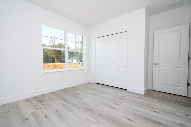 509 St Johns Ct, Poinciana, FL 34759 - unfurnished bedroom featuring light wood finished floors, baseboards, and a closet