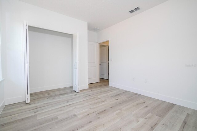 509 St Johns Ct, Poinciana, FL 34759 - unfurnished bedroom with light wood finished floors, baseboards, and a closet