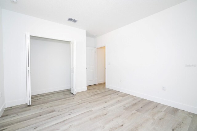 509 St Johns Ct, Poinciana, FL 34759 - unfurnished bedroom with light wood finished floors, baseboards, and a closet