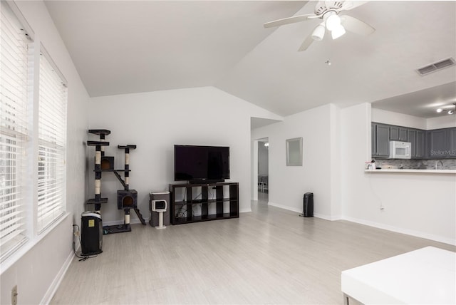 3832 NW 27th St, Gainesville, FL 32605 - living area featuring light wood-style floors, vaulted ceiling, ceiling fan, and baseboards
