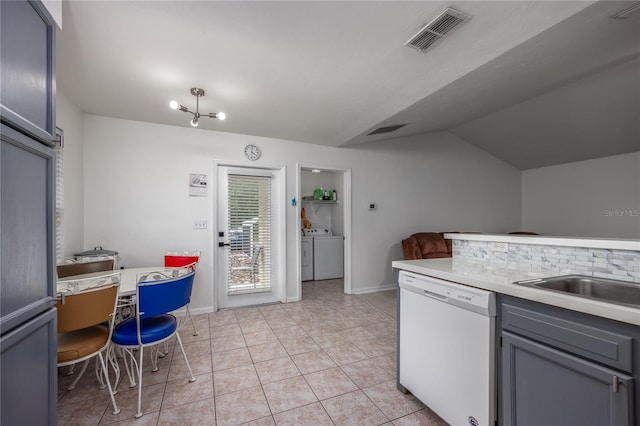 3832 NW 27th St, Gainesville, FL 32605 - kitchen with white dishwasher, lofted ceiling, light countertops, washer and clothes dryer, and baseboards