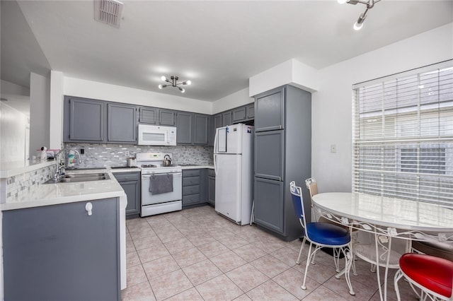 3832 NW 27th St, Gainesville, FL 32605 - kitchen featuring white appliances, a sink, light countertops, light tile patterned floors, and gray cabinets