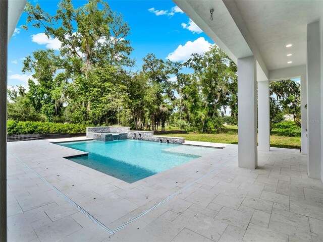 7615 SE 12th Cir, Ocala, FL 34480 - view of swimming pool featuring a patio area, view of wooded area, and a pool with connected hot tub