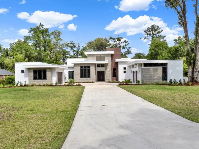 7615 SE 12th Cir, Ocala, FL 34480 - contemporary home with concrete driveway, stucco siding, a front yard, and stone siding
