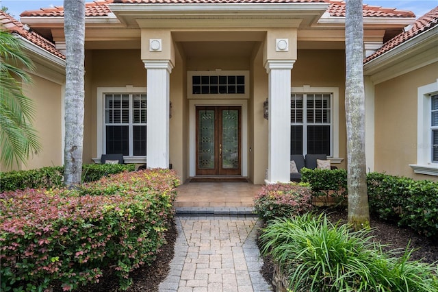 8475 Eagles Loop Cir, Windermere, FL 34786 - view of exterior entry with stucco siding, french doors, a tile roof, and covered porch