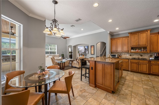 8475 Eagles Loop Cir, Windermere, FL 34786 - kitchen with arched walkways, crown molding, brown cabinetry, a chandelier, and tasteful backsplash