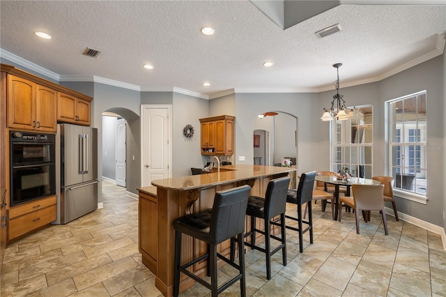 8475 Eagles Loop Cir, Windermere, FL 34786 - kitchen with arched walkways, high end fridge, brown cabinetry, a breakfast bar, and recessed lighting