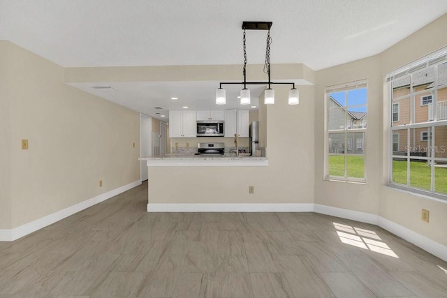2040 Royal Bay Blvd Unit 31, Kissimmee, FL 34746 - kitchen with stainless steel appliances, baseboards, white cabinetry, light countertops, and plenty of natural light