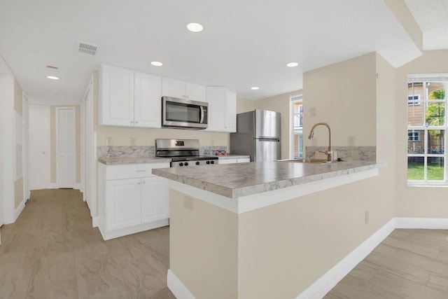 2040 Royal Bay Blvd Unit 31, Kissimmee, FL 34746 - kitchen featuring stainless steel appliances, a sink, baseboards, a peninsula, and white cabinetry