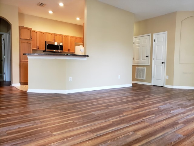 3658 Oakdale Cir Unit 100, Oviedo, FL 32765 - kitchen featuring stainless steel microwave, wood finished floors, dark countertops, arched walkways, and recessed lighting