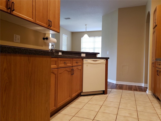 3658 Oakdale Cir Unit 100, Oviedo, FL 32765 - kitchen featuring white dishwasher, brown cabinets, a peninsula, decorative light fixtures, and baseboards
