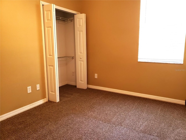 3658 Oakdale Cir Unit 100, Oviedo, FL 32765 - unfurnished bedroom featuring dark colored carpet, a closet, and baseboards