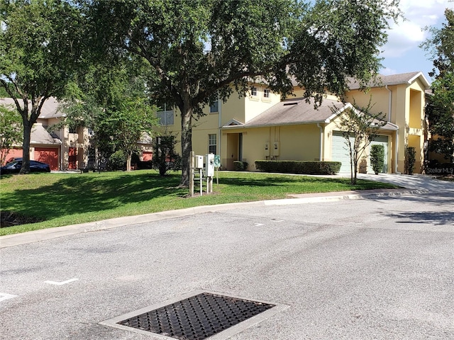3658 Oakdale Cir Unit 100, Oviedo, FL 32765 - obstructed view of property with a front yard, an attached garage, stucco siding, and driveway