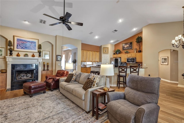 612 Golden Dawn, Apopka, FL 32712 - living area with arched walkways, ceiling fan, light wood finished floors, a tiled fireplace, and high vaulted ceiling
