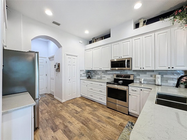 27143 Nostalgia Dr, Leesburg, FL 34748 - kitchen featuring appliances with stainless steel finishes, a sink, arched walkways, backsplash, and recessed lighting