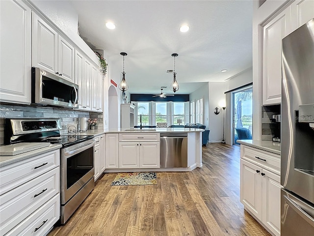 27143 Nostalgia Dr, Leesburg, FL 34748 - kitchen featuring appliances with stainless steel finishes, tasteful backsplash, a peninsula, white cabinets, and recessed lighting