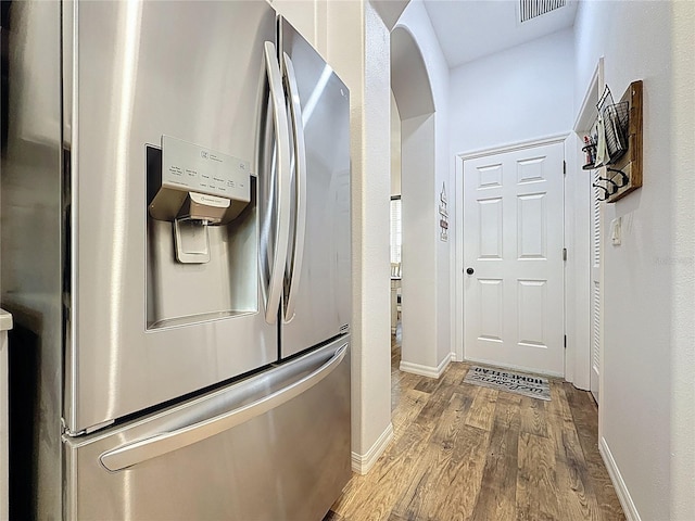 27143 Nostalgia Dr, Leesburg, FL 34748 - kitchen with stainless steel fridge with ice dispenser, wood finished floors, baseboards, and arched walkways