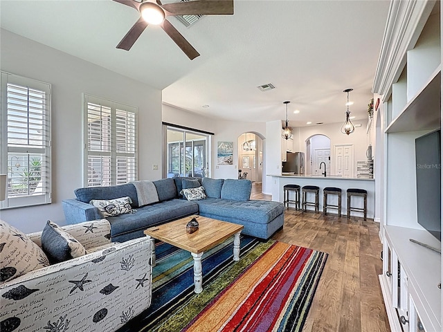 27143 Nostalgia Dr, Leesburg, FL 34748 - living room with arched walkways, a ceiling fan, dark wood finished floors, and recessed lighting