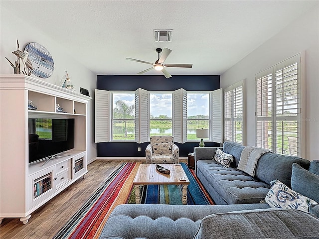27143 Nostalgia Dr, Leesburg, FL 34748 - living area with wood finished floors, baseboards, ceiling fan, and a textured ceiling