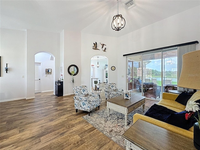 27143 Nostalgia Dr, Leesburg, FL 34748 - living room featuring arched walkways, wood finished floors, a towering ceiling, a chandelier, and baseboards