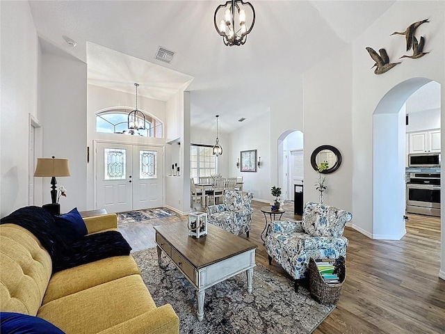 27143 Nostalgia Dr, Leesburg, FL 34748 - living area with a chandelier, arched walkways, high vaulted ceiling, wood finished floors, and baseboards