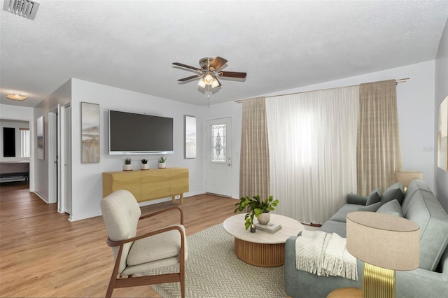 8443 SW 109th Pl, Ocala, FL 34481 - living room featuring light wood-style floors, a ceiling fan, baseboards, and a textured ceiling
