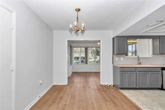 8443 SW 109th Pl, Ocala, FL 34481 - kitchen with gray cabinets, a sink, light countertops, a chandelier, and a textured ceiling