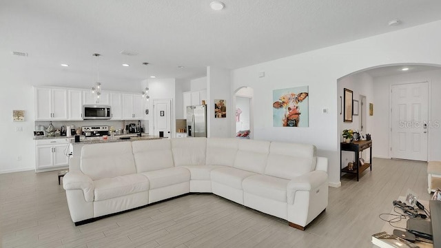 6013 Mount Zion Cir, Deland, FL 32724 - living area featuring arched walkways, light wood finished floors, recessed lighting, and baseboards