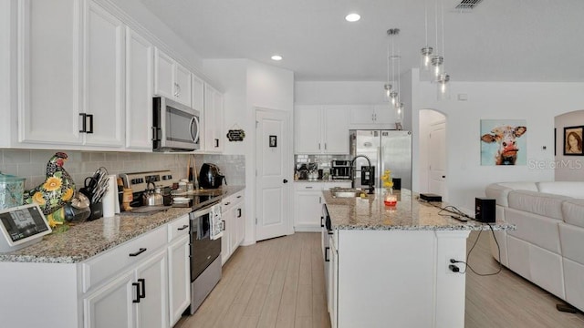 6013 Mount Zion Cir, Deland, FL 32724 - kitchen with stainless steel appliances, a sink, open floor plan, light wood-style floors, and tasteful backsplash