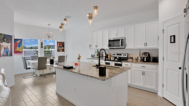 6013 Mount Zion Cir, Deland, FL 32724 - kitchen featuring stainless steel appliances, a sink, light wood-type flooring, a chandelier, and white cabinets